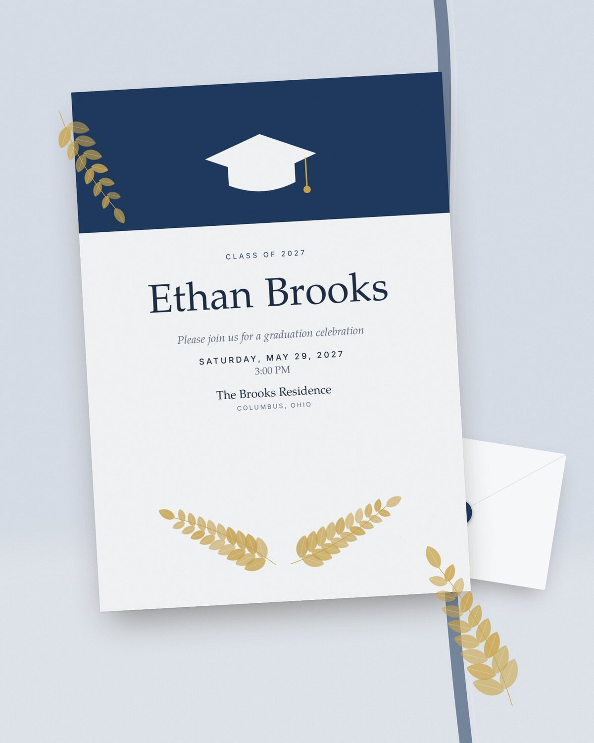 Cap & Laurel navy and gold graduation party invitation, styled flat-lay with envelope